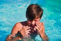 The teenager hides his face with his hands in the pool, wiping water from his eyes while swimming in the pool. Eye Royalty Free Stock Photo