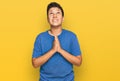 Teenager hispanic boy wearing casual clothes begging and praying with hands together with hope expression on face very emotional