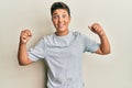 Teenager hispanic boy wearing casual grey t shirt celebrating surprised and amazed for success with arms raised and open eyes Royalty Free Stock Photo