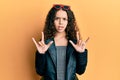 Teenager hispanic girl doing rock gesture clueless and confused expression
