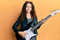 Teenager hispanic girl playing electric guitar smiling with a happy and cool smile on face