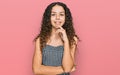 Teenager hispanic girl wearing casual clothes looking confident at the camera with smile with crossed arms and hand raised on chin Royalty Free Stock Photo