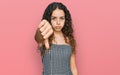 Teenager hispanic girl wearing casual clothes looking unhappy and angry showing rejection and negative with thumbs down gesture Royalty Free Stock Photo