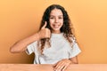 Teenager hispanic girl wearing casual clothes sitting on the table doing happy thumbs up gesture with hand Royalty Free Stock Photo