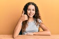 Teenager hispanic girl wearing casual clothes sitting on the table doing happy thumbs up gesture with hand Royalty Free Stock Photo