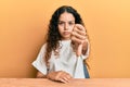 Teenager hispanic girl wearing casual clothes sitting on the table looking unhappy and angry showing rejection and negative with Royalty Free Stock Photo