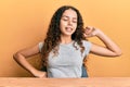 Teenager hispanic girl wearing casual clothes sitting on the table stretching back, tired and relaxed, sleepy and yawning for Royalty Free Stock Photo