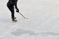 Teenager with hockey stick, wearing ice-skating, skates and drags the puck. Active sport outdoor