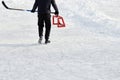 Teenager with hockey stick, wearing sneakers, goes to little training red goal on park ice rink. Active sport outdoor