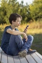 Teenager Holded in Hand Smartphone . Boy look in cell phone and take picture on summer background Royalty Free Stock Photo