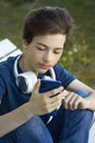 Teenager Holded in Hand Smartphone . Boy look in cell phone and take picture on summer background