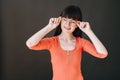 A teenager holds round glasses with her hands and looks away on a black background Royalty Free Stock Photo