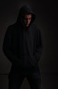 Teenager with hoodie looking down on black background