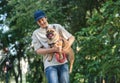 Teenager hugs his red french bulldog outside. Boy walking with cute bulldog in the park. Still life, friendship with a dog.