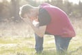 Teenager on knee and praying in open field