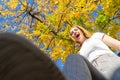 Teenager laughing steeping the camera on a fight with her shoes with a autumn leaves tree