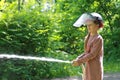 Teenager learning the firefighter profession. The girl in the fire helmet pours water from the hose Royalty Free Stock Photo