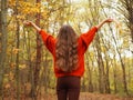 A teenager lifting her hands up with joy. A girl wearing orange sweater and brown jeans