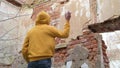 The teenager looks at the old ruined wall appraisingly and shakes the spray can