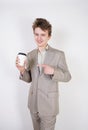 Teenager male in gray business suit with paper Cup of coffee in hand on white studio background Royalty Free Stock Photo