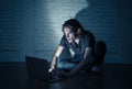 Teenager man suffering Internet cyber bullying sitting alone with computer feeling hopeless