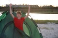 Teenager meets dawn in tent on the river bank. Camping holiday in countryside