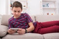 Teenager messaging online on smartphone in living room at home