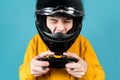 A teenager in a motorcycle helmet with a joystick from a game console winks