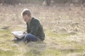 Teenager in open field reading Bible