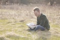 Teenager in open field reading Bible