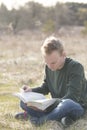 Teenager in open field reading Bible