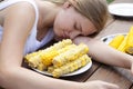 Girl eating lot boiled corn. Putting your head on the table