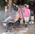 Siem Reap, Cambodia, December 17, 2018 teenager in a pink t-shirt, cap and rubber boots washes a scooter. Motor scooter in white