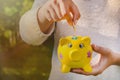 Teenage girl places coin into piggy bank to save for the future