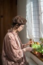 Teenager plant lover examining houseplant, tearing away dry leaves. Domestic life, ecological hobby