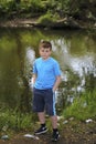 A teenager poses for a photographer while walking in a park by the river.