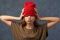 Teenager pulling down red hat, keeping eyes closed