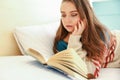 Teenager reading a book in bed