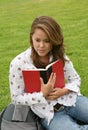 Teenager reading book on grass