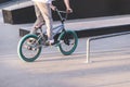 teenager rides a blue BMX bike on a skate park and is about to make a trick. A young man rides a BMX bike. BMX culture