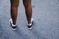 Teenager's feet in a pair of black canvas All-Stars casual shoes stands on urban asphalt road Royalty Free Stock Photo