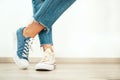 Teenager`s feet posing in casual different colors beige and blue new sneakers on the white wooden floor close up image. Vintage Royalty Free Stock Photo