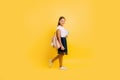 A teenager with a backpack and books. Stylish beautiful schoolgirl posing on a yellow background