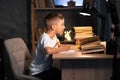 teenager schoolboy at the table doing homework at home at night, boy writes a test with a pen in a notebook while Royalty Free Stock Photo