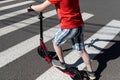 A teenager with a scooter crosses the road at a pedestrian crossing. Road safety Royalty Free Stock Photo