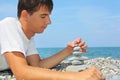 Teenager on seacoast, creates pyramid from pebble