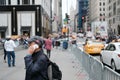 Teenager seen using a phone in a public place in New York City during early autumn on a busy working day.