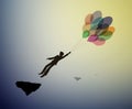 Teenager silhouette holds the baloons and flying up to the sky, strong wind story, dreamer concept, scene in dreamland