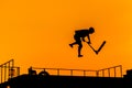 Teenager silhouette showing high jump tricks on scooter against orange sky Royalty Free Stock Photo