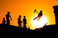 Teenager silhouette showing high jump tricks on scooter against orange sky Royalty Free Stock Photo